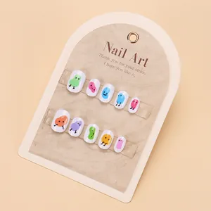 Detalle de coloridos dibujos animados en uñas postizas blancas para niñas con tarjetero