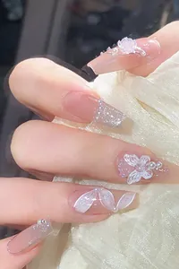 Macro detail of nude press-on nails featuring 3D butterflies, floral art and glitter