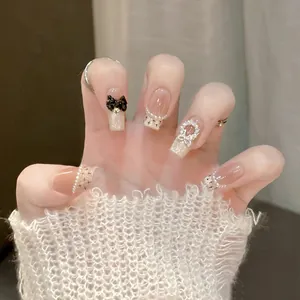 Detail of press-on nails with silver glitter, black 3D bow, and pearl accents