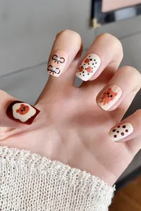 Detail of sweet cartoon bear press-on nails with 3D pearl bow and red polka dots