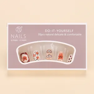 Detail of cute brown bear cartoon press-on nails in cream tones with bow tie design