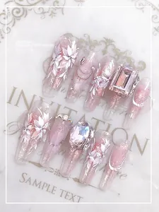 Detail of pink cat-eye press-on nails with hand-painted flowers and large pink rhinestone