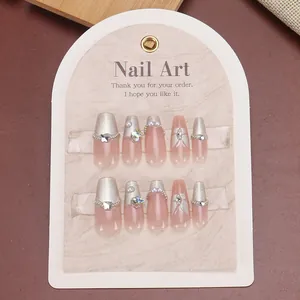 Pink cat-eye press-on nails with 3D butterflies and pearls on a display card