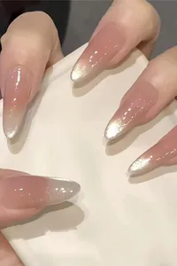 Macro view of stiletto press-on nails with nude pink and silver glitter gradient