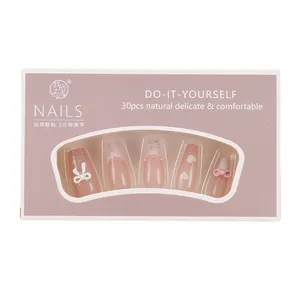 Pink heart French press-on nails with bow and pearl detail in premium packaging