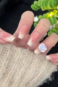 Close-up of pink gradient press-on nails with French V-tip and 3D acrylic flower design