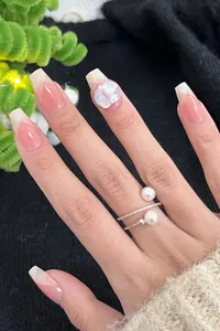 Detail of pink French gradient press-on nails with aurora crystals and pearl rings
