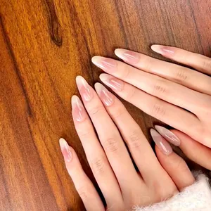 Gros plan d'ongles longs en amande avec dégradé French rose et blanc sur fond de bois