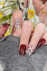 Detail of handmade cat-eye press-on nails with silver bow charms and glitter
