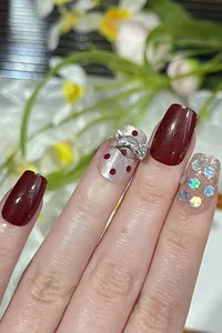 Detailed view of burgundy cat-eye nails with silver dots, metallic bows and laser sequins
