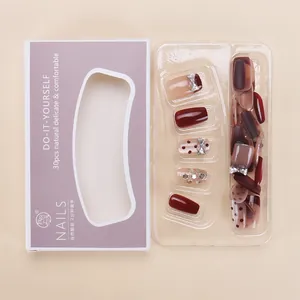 Detail of luxury press-on nails set in burgundy cat-eye with rhinestone accents in box
