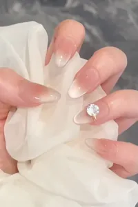 Detail of pink gradient press-on nails with large round rhinestone and satin fabric
