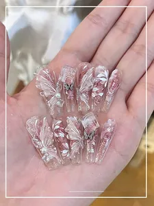 Detail of soft pink gradient press-on nails with 3D butterflies, pearls, and silver glitter