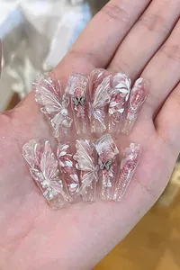 Detail of long coffin press-on nails with butterfly charms, pearls, and pink glitter