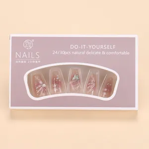Detail of pink press-on nails with 3D floral pearls and butterfly charms in package