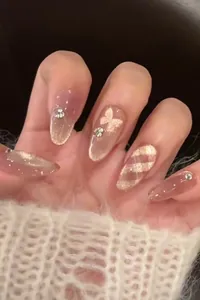 Detail of pink cat eye press-on nails with 3D gold butterflies and sparkling rhinestones