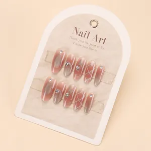 Handmade cat-eye press-on nails with butterfly designs and rhinestones on beige card
