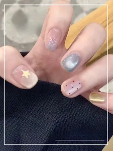 Détail de faux ongles effet œil-de-chat avec étoiles argentées et motifs à pois rouges