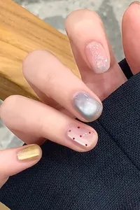 Détail de faux ongles avec effet œil de chat, paillettes roses et fini doré métallisé