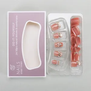 Detail of coral pink cat-eye press-on nails with rhinestones and gradient purple packaging