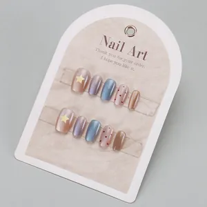 Détail de faux ongles avec motifs étoiles, effet œil de chat et pois sur carte de support