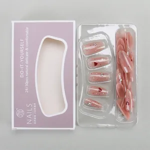 Detail of nude pink press-on nails set with red hearts and rhinestones in purple box