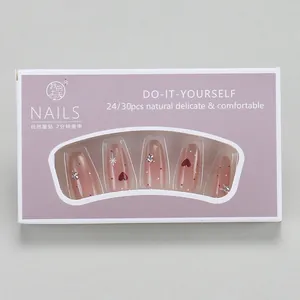 Close-up of pink press-on nails with red heart rhinestones in its original packaging
