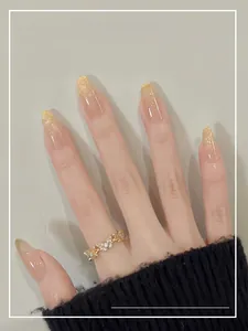 Detailed macro of champagne gold glitter gradient press-on nails with a butterfly ring