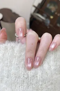 Detail of short oval cat-eye press-on nails in sheer nude pink with glossy finish