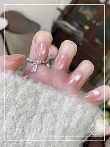 Détail de faux ongles œil de chat rose avec texture gelée portés avec une bague