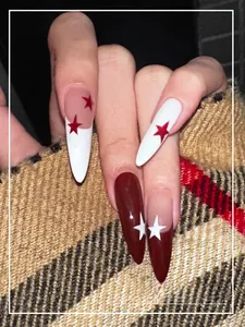 Detailed view of long almond press-on nails with red star patterns and wine red glossy finish