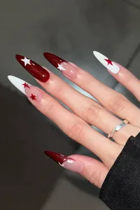 Detail of long almond nails with deep burgundy and white star design on human hand