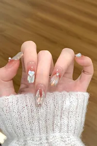 Detail von handgemachten Kunstnägeln mit 3D-Herzen, Perlen und Muschel-Textur in Rosé