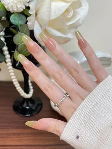 Detalle de uñas postizas almendradas con degradado rosa y verde, acabado brillo