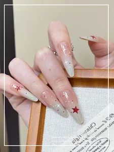 Macro shot of long stiletto press-on nails with star patterns and pink gradient finish
