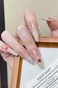 Detail view of long stiletto nails with gradient pink base and red star patterns