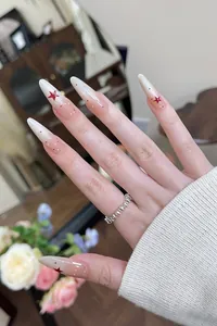 Detail of almond-shaped press-on nails with star patterns and pink gradient finish