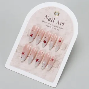 Detail of almond-shaped press-on nails with pink-grey gradient and star patterns