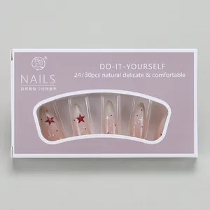 Detail of gradient pink almond press-on nails with star patterns in windowed box packaging