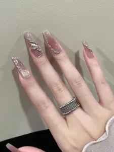 Detailed view of long coffin nails with nude pink gradient, rhinestones and silver glitter