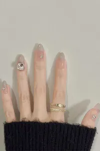 Close-up of cat-eye press-on nails with rhinestones and coffee gradient finish