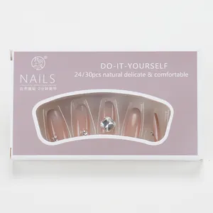 Detail of nude pink gradient press-on nails set with rhinestones in lavender packaging