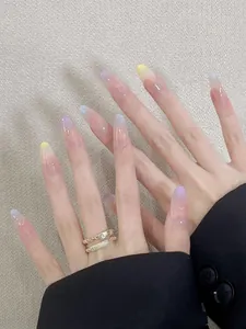 Détail macro de faux ongles amande avec dégradé pastel coloré et finition pailletée fine