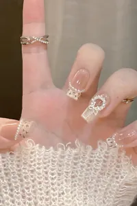 Detailed view of French pink nails with pearls, rhinestone bows, and silver ring