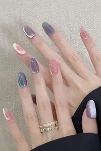 Close-up of cat-eye press-on nails in purple and pink with gold designer rings