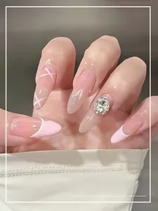 Dettaglio di unghie finte French rosa con fiocchi bianchi e decorazioni in strass