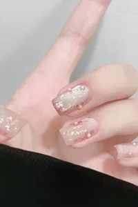 Détails d'ongles rose gelée avec motifs floraux, feuilles d'or et mini-perles