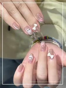 Détail de faux ongles œil de chat roses avec nœuds 3D et motifs de chat mignons