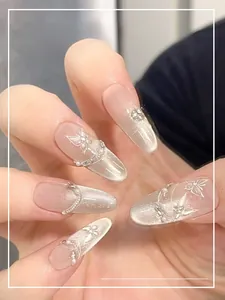 Detail of pink cat-eye press-on nails with 3D butterfly, silver lines, and pearls