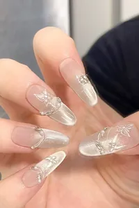 Detail of cat eye press-on nails with handmade butterfly art and tiny pearl accents